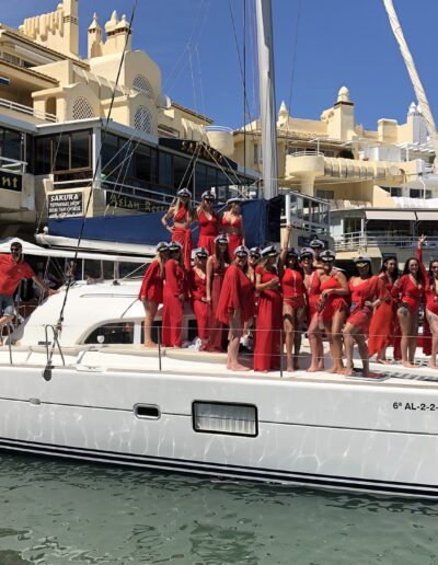 Group of girls dressed in red and the bride in white celebrating a bachelorette party on a boat in Benalmádena