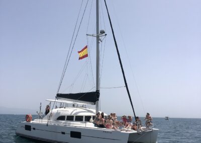 People enjoying a catamaran boat ride in Benalmádena, sailing on crystal-clear waters